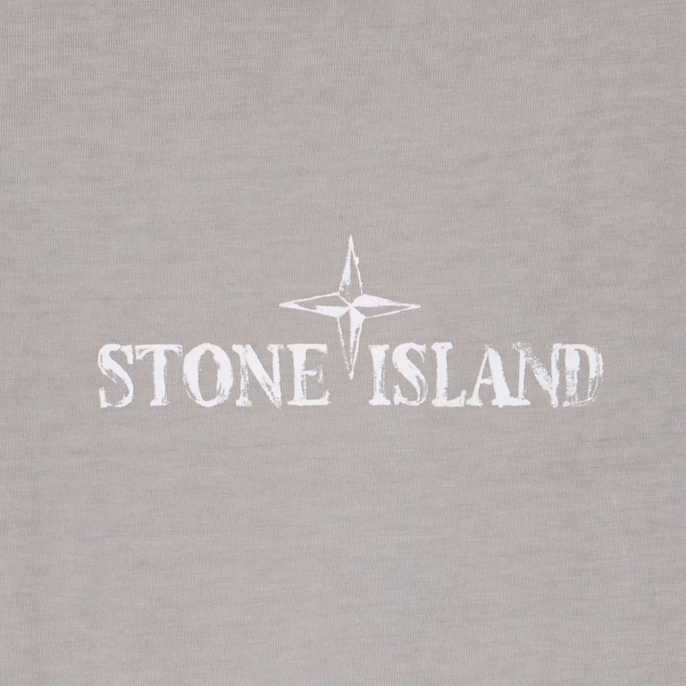 Close-up of a light gray fabric surface with a white Stone Island compass logo and text printed across the center.