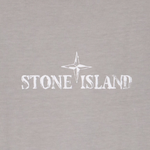 Close-up of a light gray fabric surface with a white Stone Island compass logo and text printed across the center.