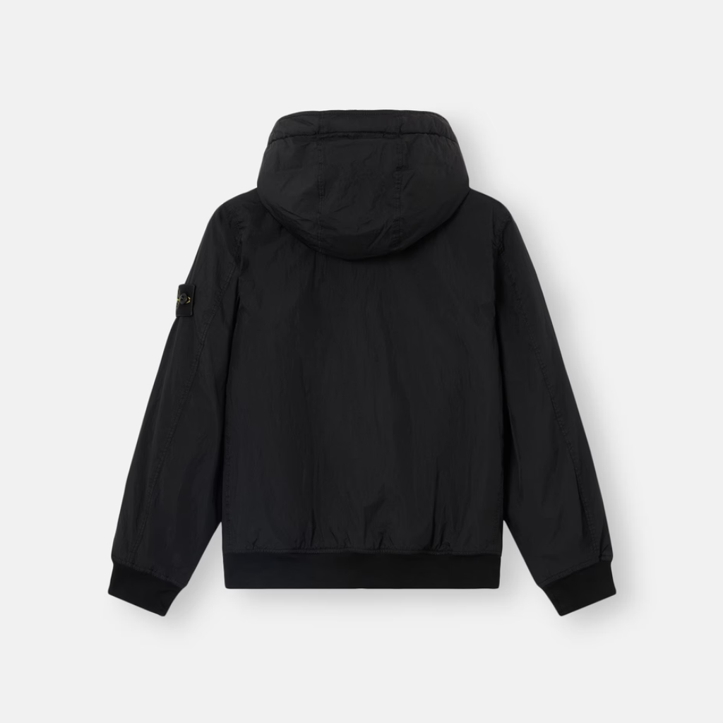 A black hooded jacket shown from the back, featuring a subtle vertical texture and a small black rectangular patch on the left sleeve, set against a light gray background.