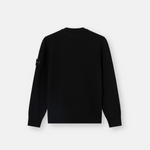 A black long-sleeve crewneck sweater shown from the back, featuring a small black and white logo patch on the left sleeve.