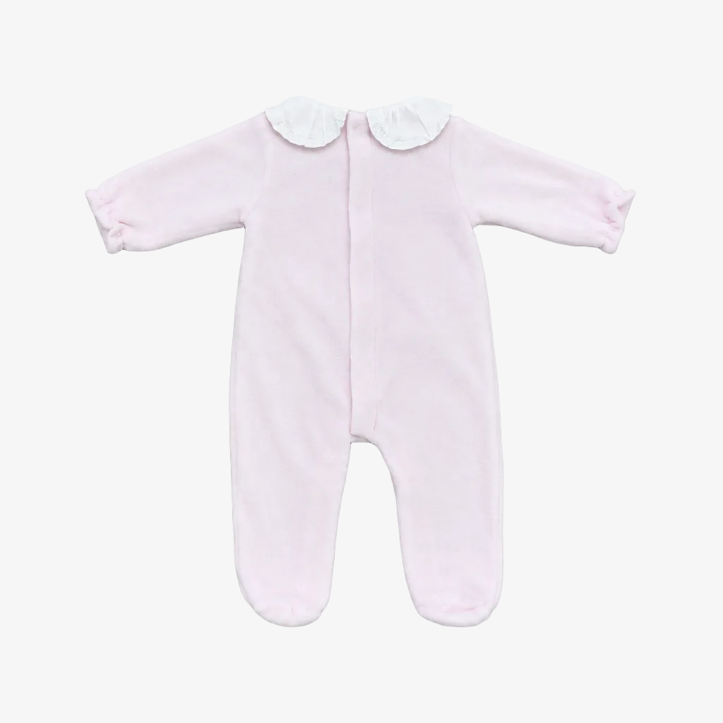 A light pink baby footed sleeper with long sleeves, a white ruffled Peter Pan collar, and an all-on-the-back zipper, laid flat on a neutral gray background.