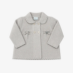 A light gray knit baby cardigan with a Peter Pan collar, three front buttons, decorative bows on the chest, and scalloped edges on the sleeves and hem, shown flat on a gray background.