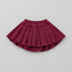 A pleated mini skirt in a deep burgundy or maroon color, laid flat against a neutral light gray background.
