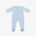 A light blue long-sleeve baby footed sleeper shown from the back, featuring a white collar and a central snap closure, laid flat on a neutral gray background.