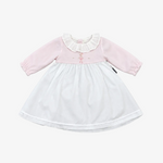 A baby girl's long-sleeve dress with a light pink bodice, white ruffled collar, and a white skirt, laid flat on a neutral gray background.