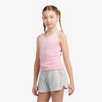 Young girl wearing a pink sleeveless top and gray shorts on a light gray background