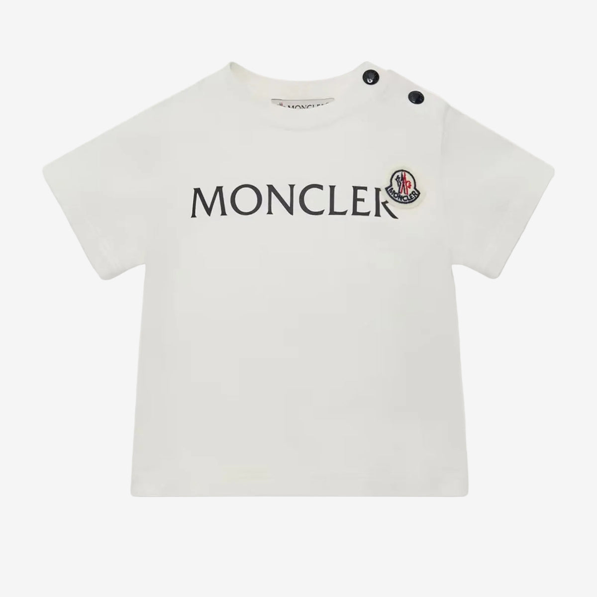 A white short-sleeve baby T-shirt by Moncler, featuring the brand name 'MONCLER' and its signature red bear logo printed on the chest, with two black snap buttons on the shoulder.