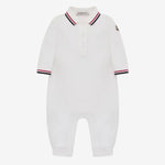 A white long-sleeve baby romper with a polo-style collar, featuring navy and red striped trim on the collar and cuffs, and a small black embroidered logo on the left sleeve.