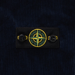 Close-up of a dark navy corduroy fabric with a black rectangular Stone Island logo patch featuring the signature compass logo.