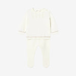 White baby outfit with long-sleeve top and footed pants on a light gray background