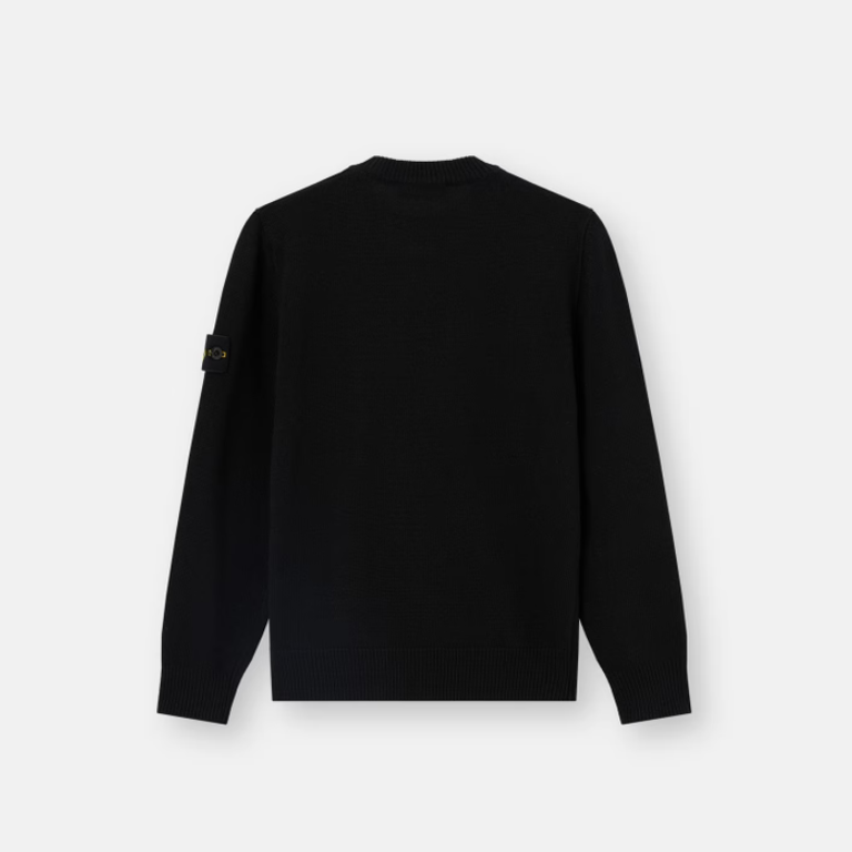 A black long-sleeve crewneck sweater shown from the back, featuring a small black and white logo patch on the left sleeve.