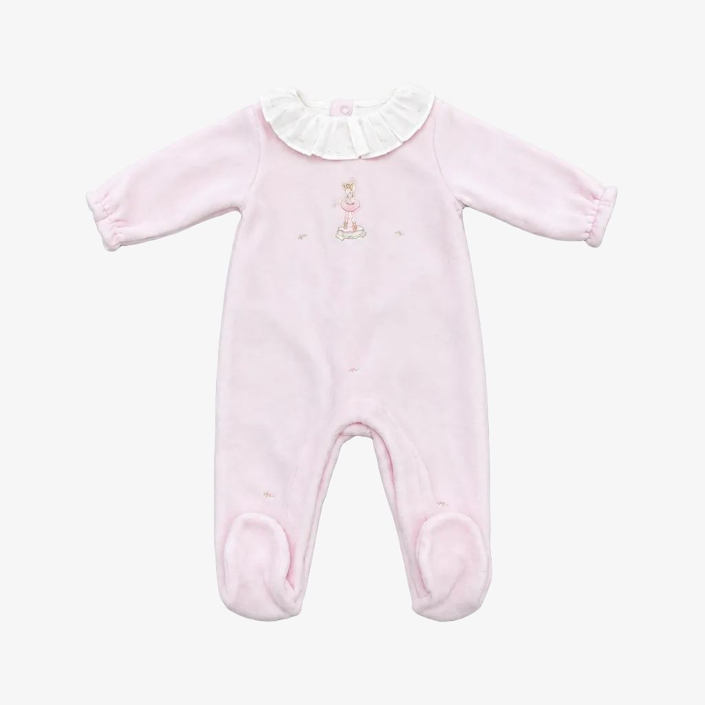 A light pink long-sleeve baby footed romper with a white ruffled collar and a small embroidered bunny on the chest, laid flat on a neutral gray background.