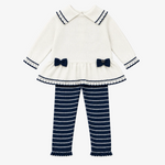 A toddler girl's two-piece knit outfit set featuring a cream long-sleeve top with navy blue trim, bow details, and a ruffled hem, paired with navy blue and cream horizontally striped pants, laid flat on a light beige background.