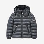 A dark gray puffer jacket with a hood, shown flat against a light gray background. The jacket features horizontal quilting, two zippered pockets on the front, and the iconic circular Moncler logo patch on the left sleeve.