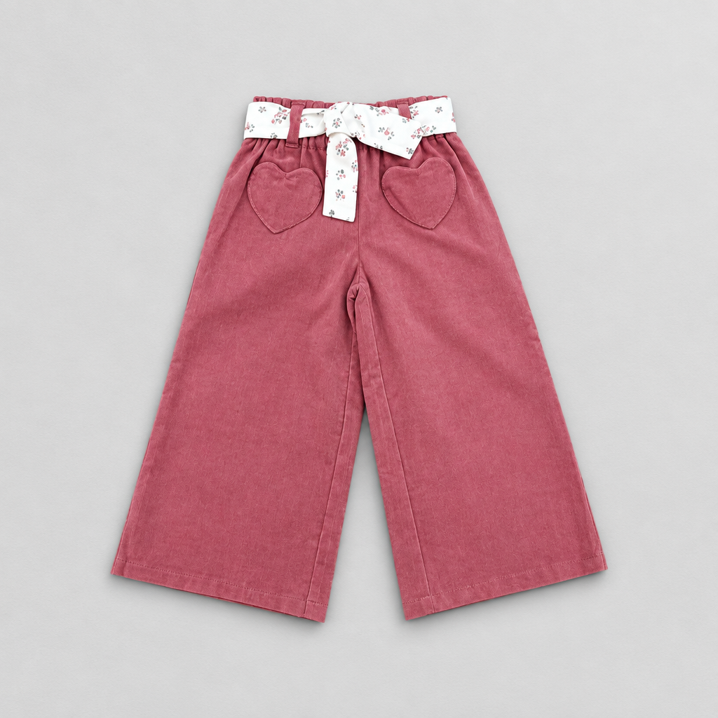 A pair of toddler's wide-leg corduroy pants in dusty rose pink, featuring a white waistband with a small floral print and a matching fabric bow, plus two heart-shaped front pockets.