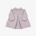 A light pink knitted baby cardigan with long sleeves, a textured cable-knit yoke, and a ruffled mock neck, laid flat on a neutral gray background.