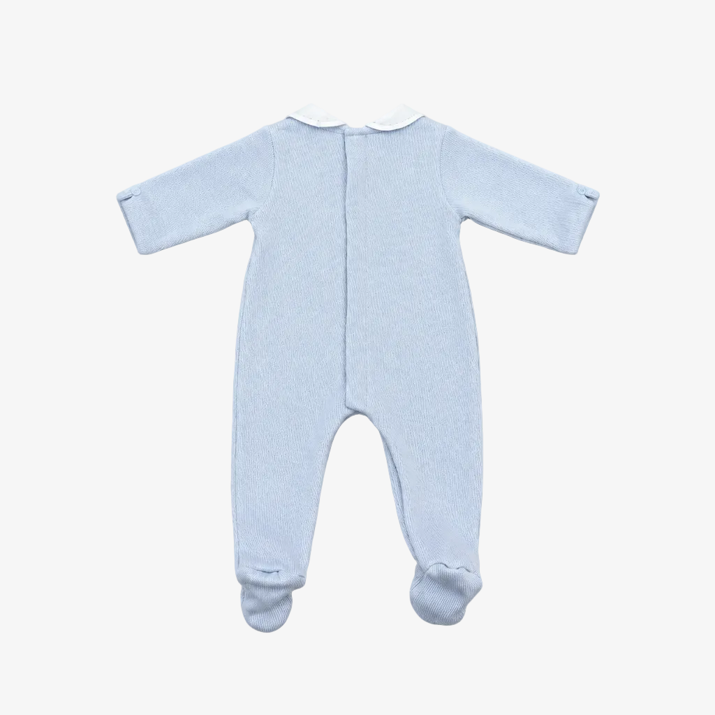 A light blue long-sleeve baby footed sleeper shown from the back, featuring a white collar and a central snap closure, laid flat on a neutral gray background.