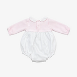 A baby long-sleeve romper in light pink and white, featuring a pink velvet-like bodice with a white ruffled Peter Pan collar and snap buttons, and a white fabric bloomers section with ruffled edges, laid flat on a neutral gray background.