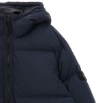 Close-up of a dark navy puffer jacket with horizontal quilting, a front zipper, and a small Stone Island compass patch on the sleeve, set against a plain white background.