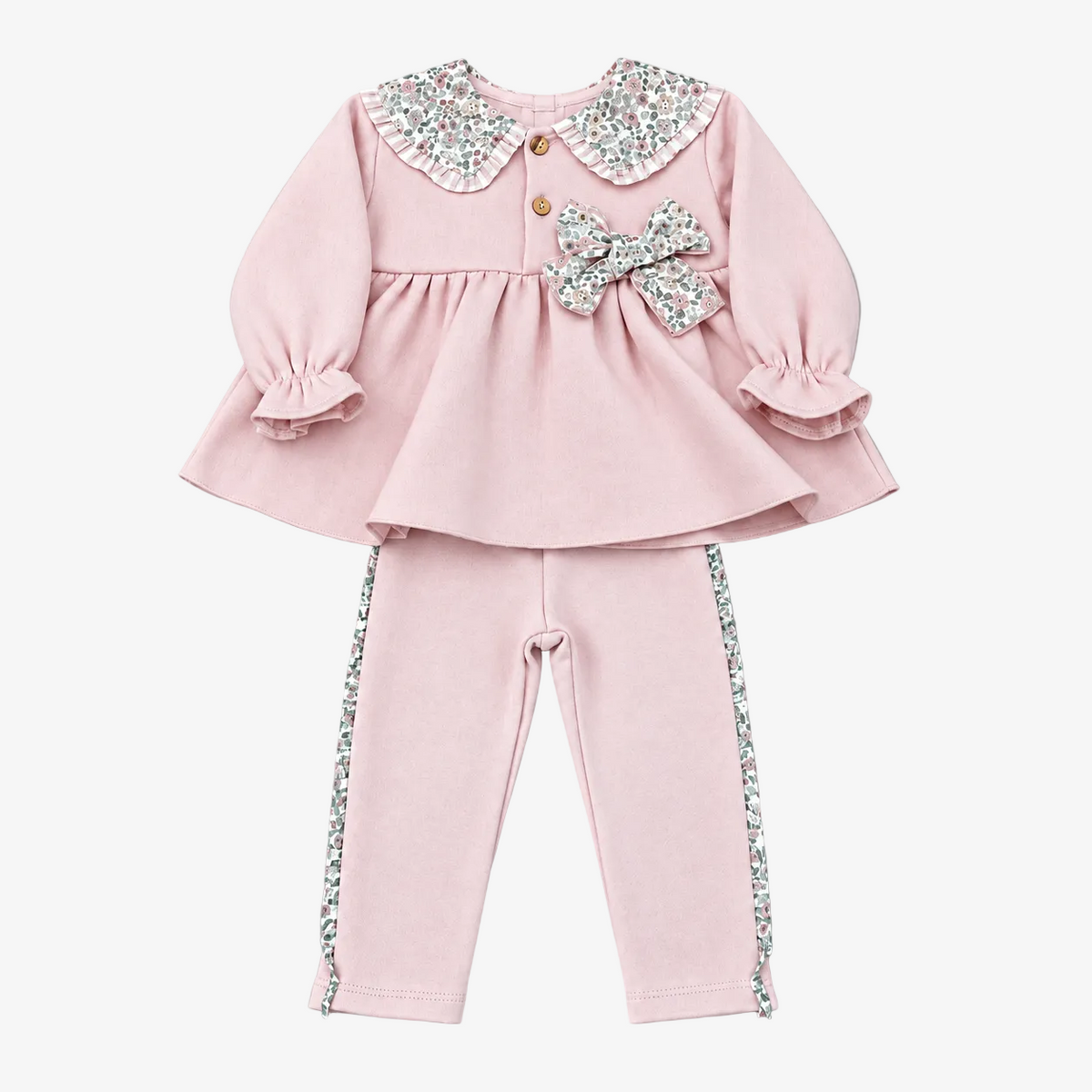 A two-piece toddler girl's outfit set in light pink, featuring a long-sleeve peplum top with a sparkly silver and white patterned Peter Pan collar, a matching bow on the chest, and matching pants with decorative side trim, laid flat on a neutral gray background.