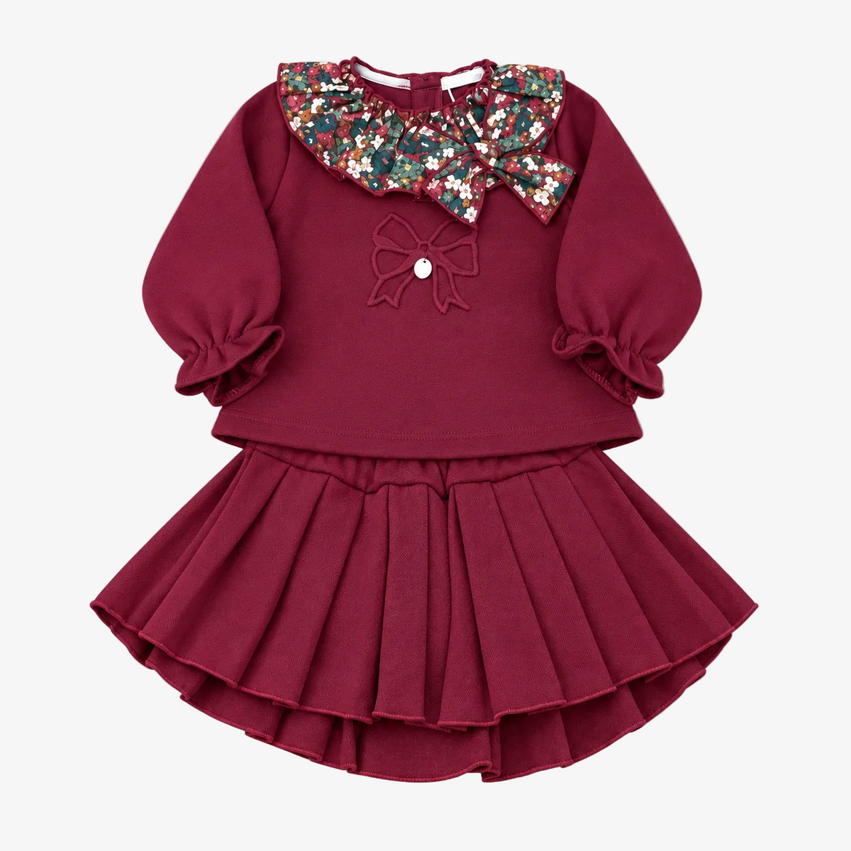 A toddler girl's two-piece outfit featuring a long-sleeve top and pleated skirt in deep burgundy. The top has a large, decorative multi-colored sequin Peter Pan collar, a matching sequin bow on the chest, and ruffled cuffs.