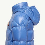 A close-up side view of a shiny blue puffer jacket with quilted padding and a hood, shown against a plain off-white background.